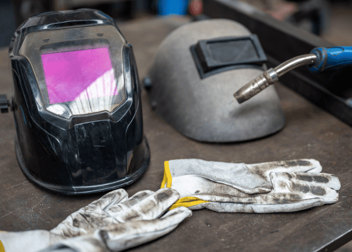 Black and grey welding helmets and white welding gloves