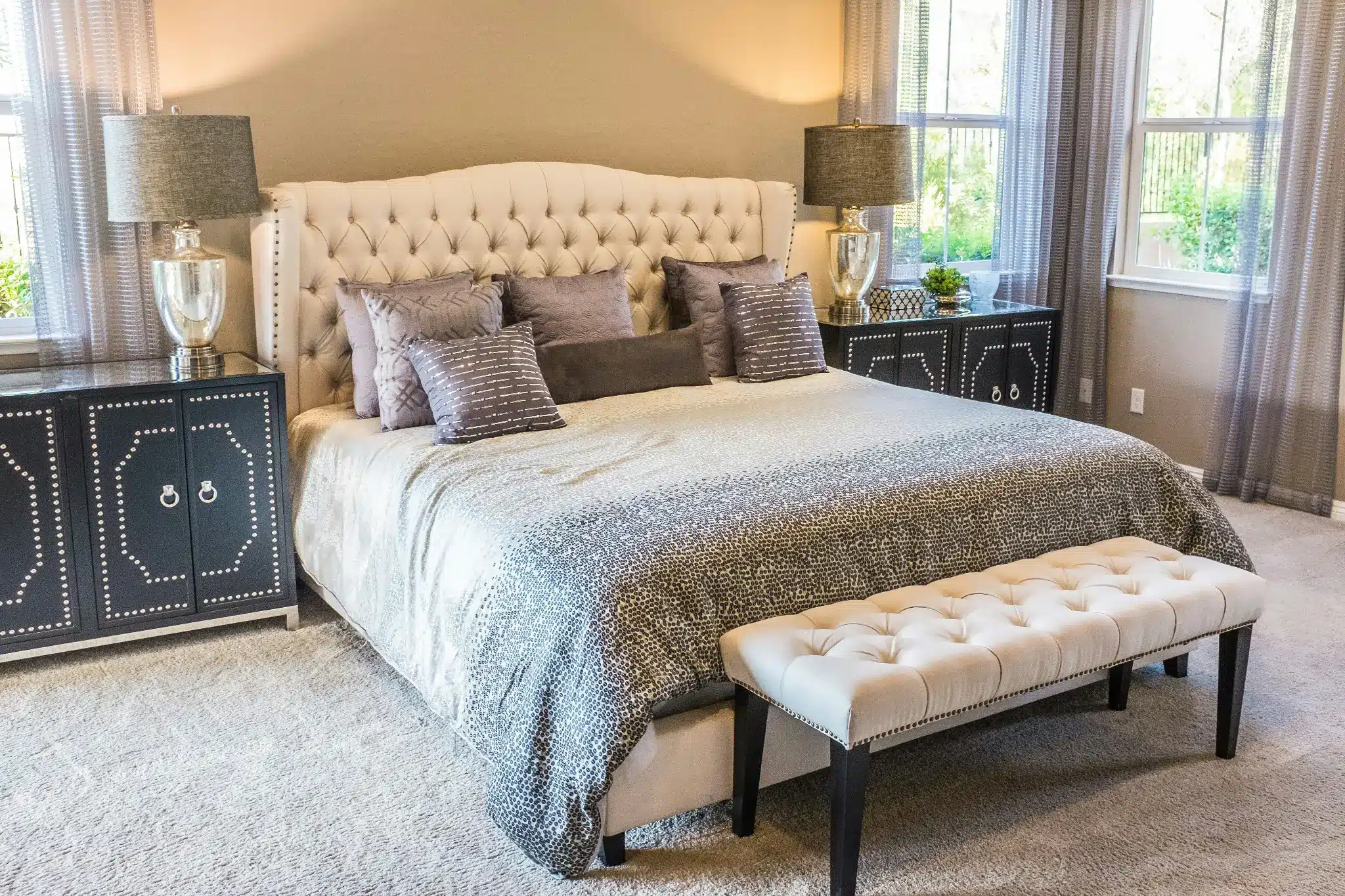 Elegant bedroom with tufted bedframe, decorative pillows, and matching bedside lamps in soft natural light