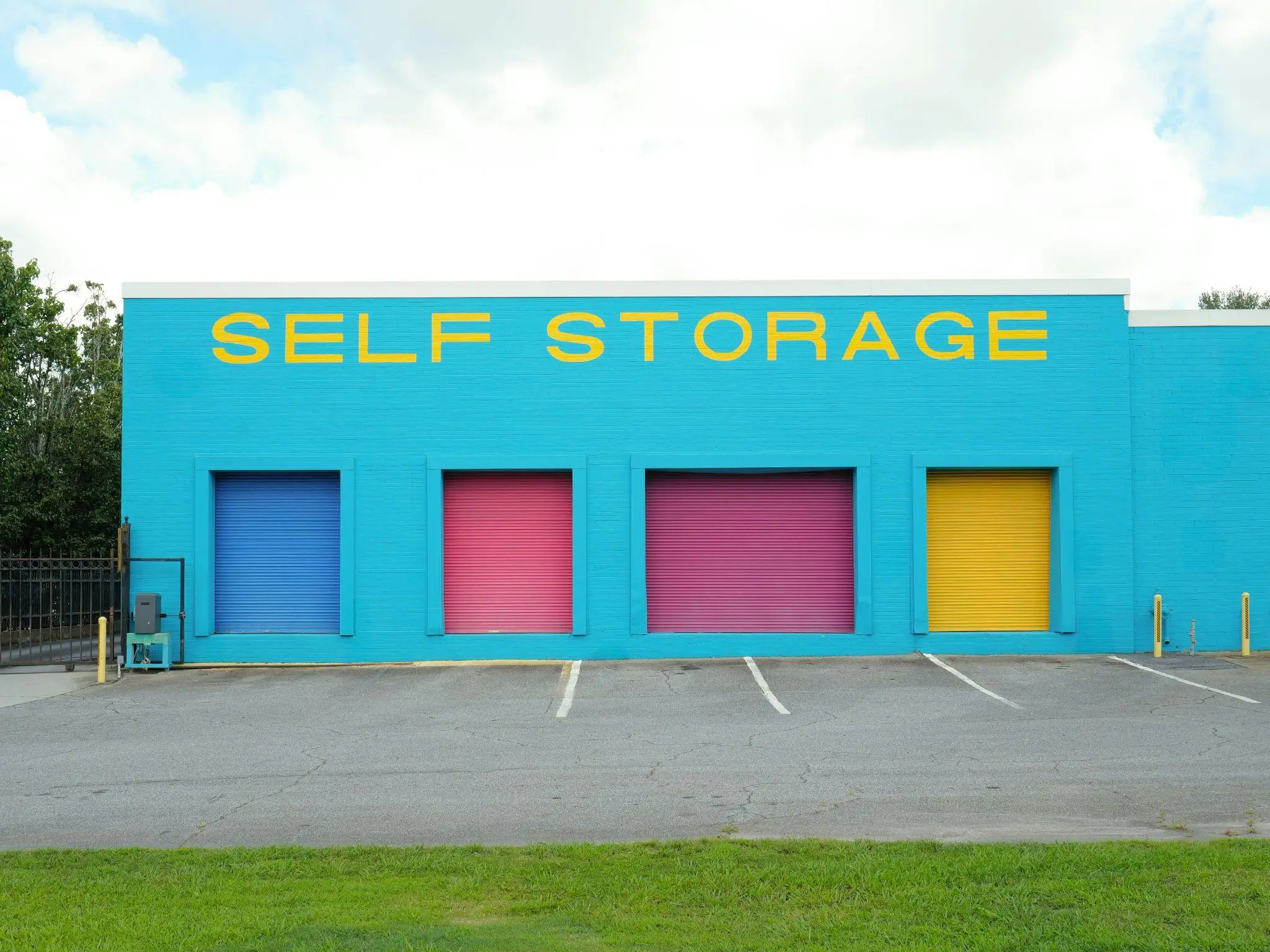 Brightly colored self-storage facility with teal walls and vibrant blue, pink, and yellow doors