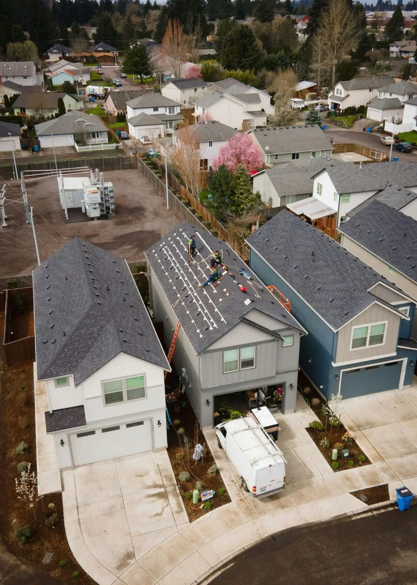 Workers installing solar panels on suburban house rooftop in residential neighborhood
