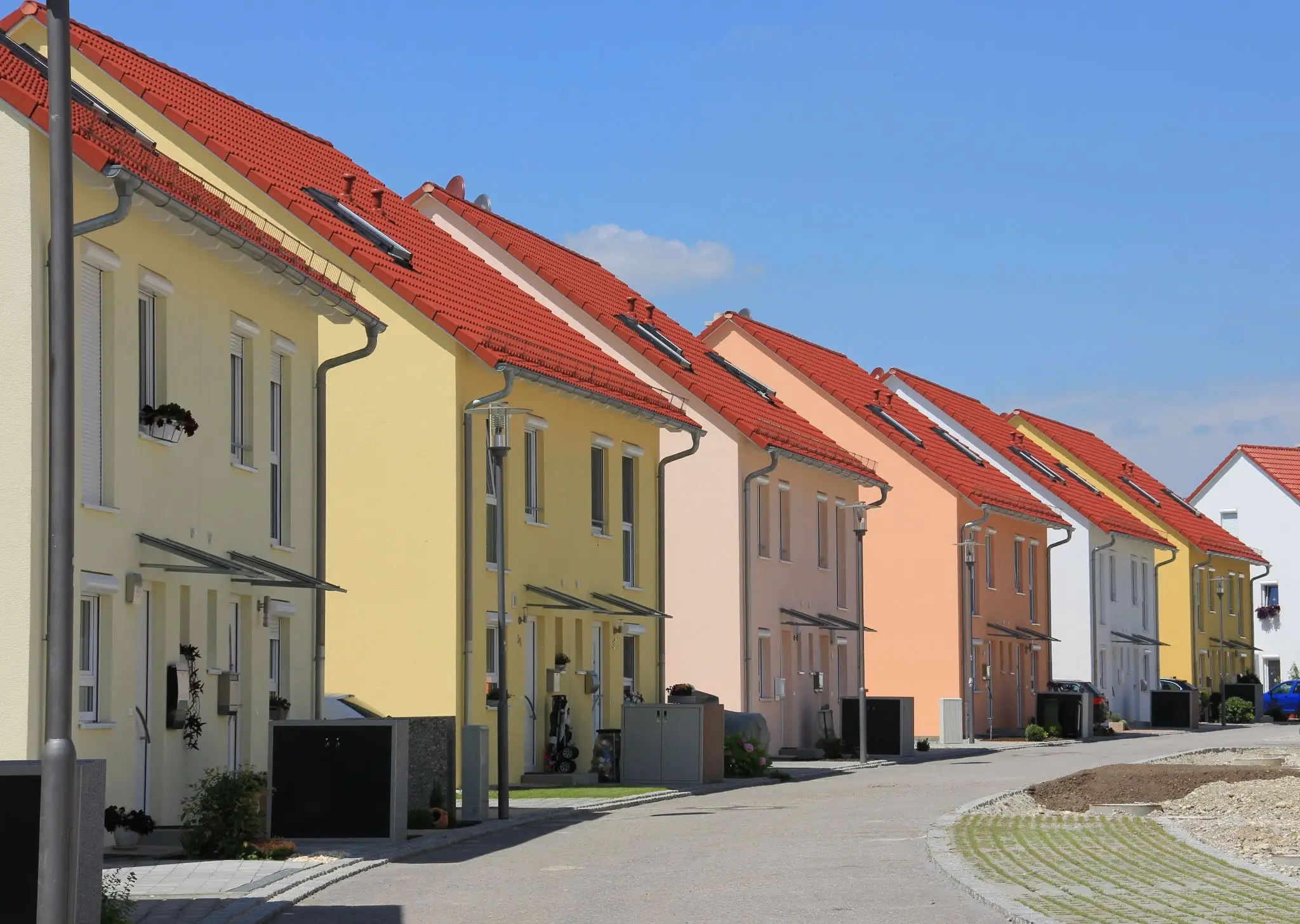 Row of colorful houses with red roofs on a sunny residential street