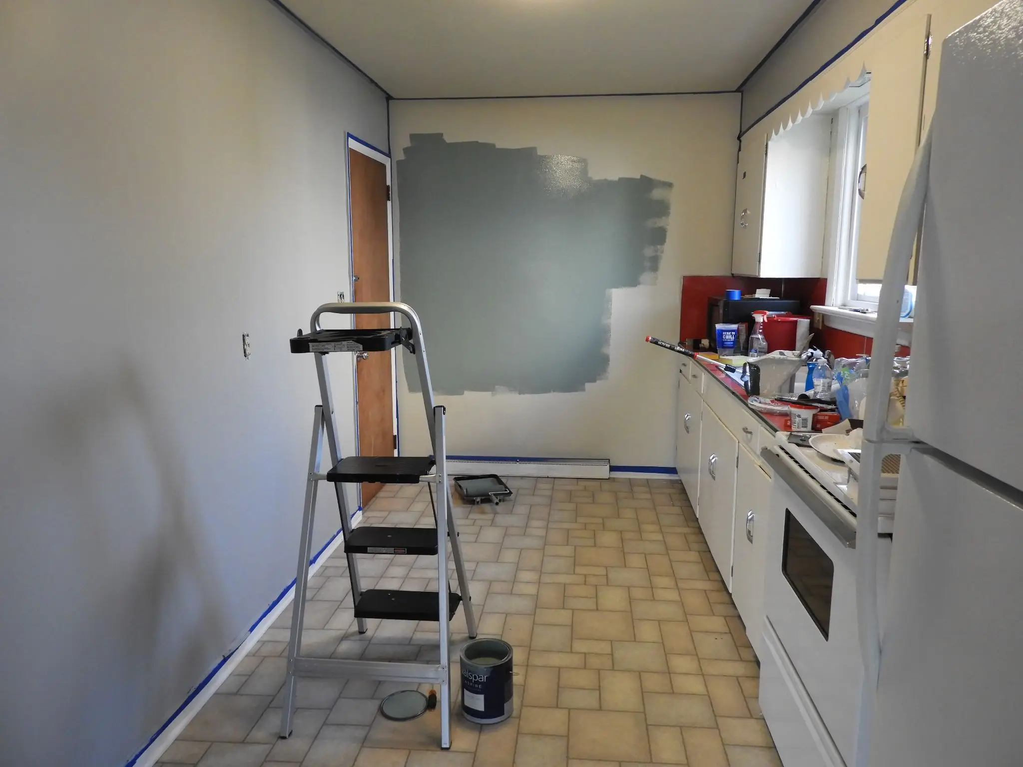 Kitchen renovation in progress with gray wall paint and ladder on tiled floor