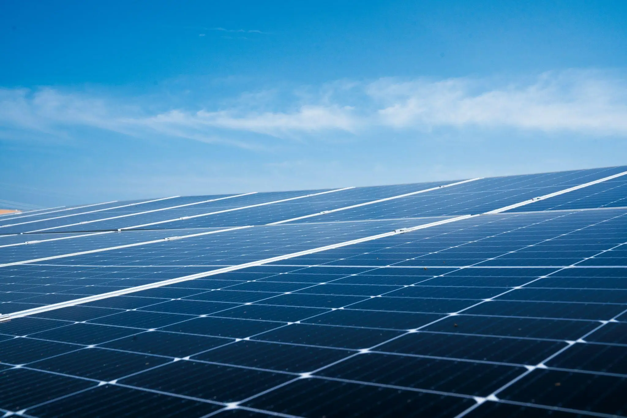 Rows of blue solar panels under clear blue sky in outdoor setting
