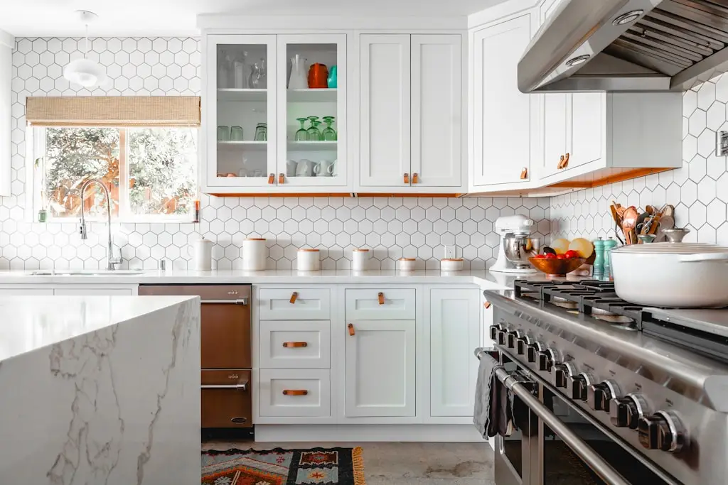 Modern kitchen with white cabinets and stainless steel appliances featuring hexagon tile backsplash