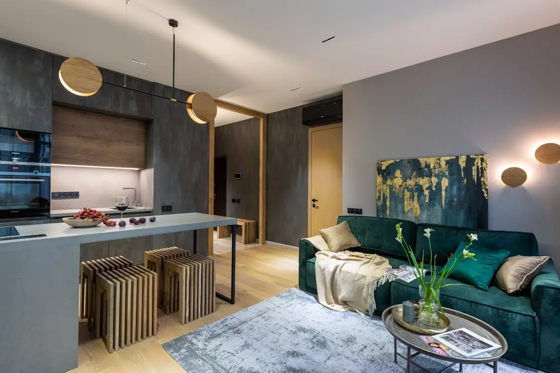 Modern living room with green velvet sofa and integrated kitchen under warm lighting