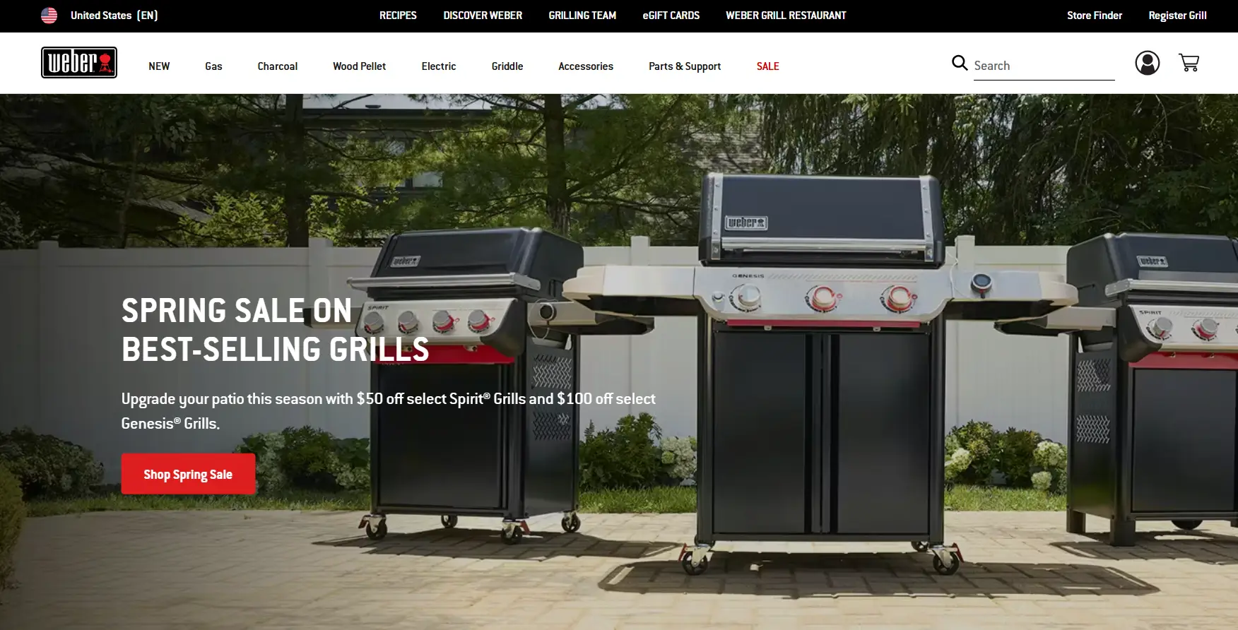 Outdoor patio with two Weber gas grills on a sunny day in front of white fence