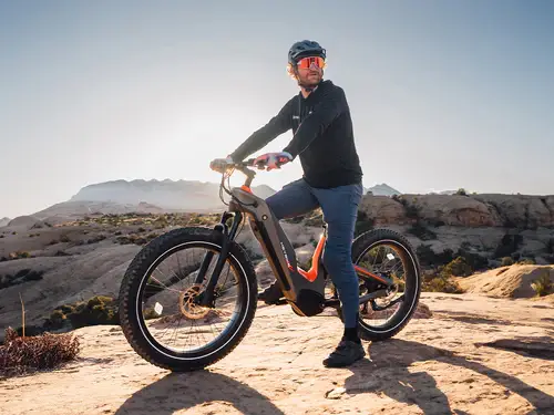 Person on electric mountain bike on rocky terrain under clear blue sky