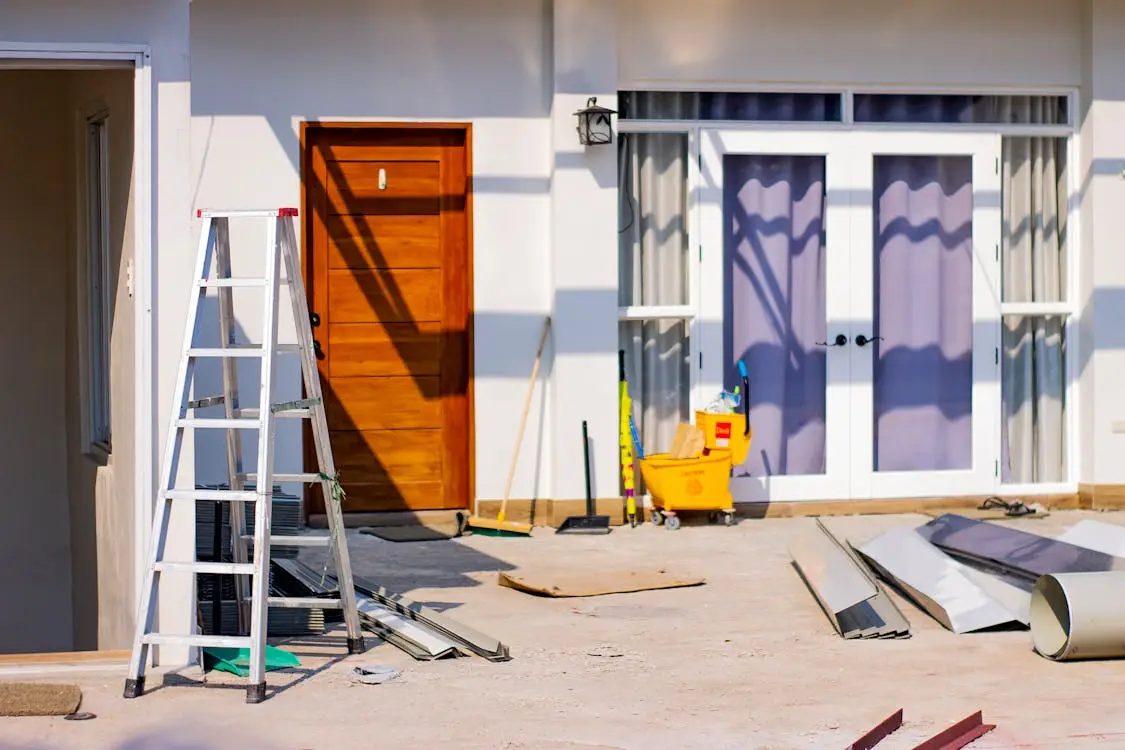 Construction site with ladder and materials outside a building door in bright sunlight