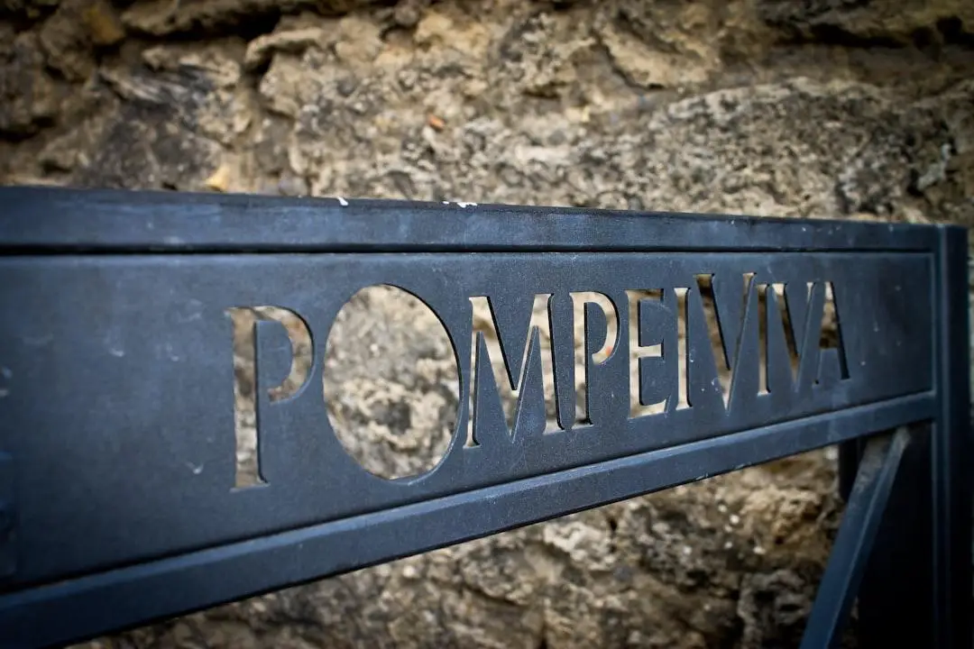 Black metal sign with cut-out letters against a rough stone wall background