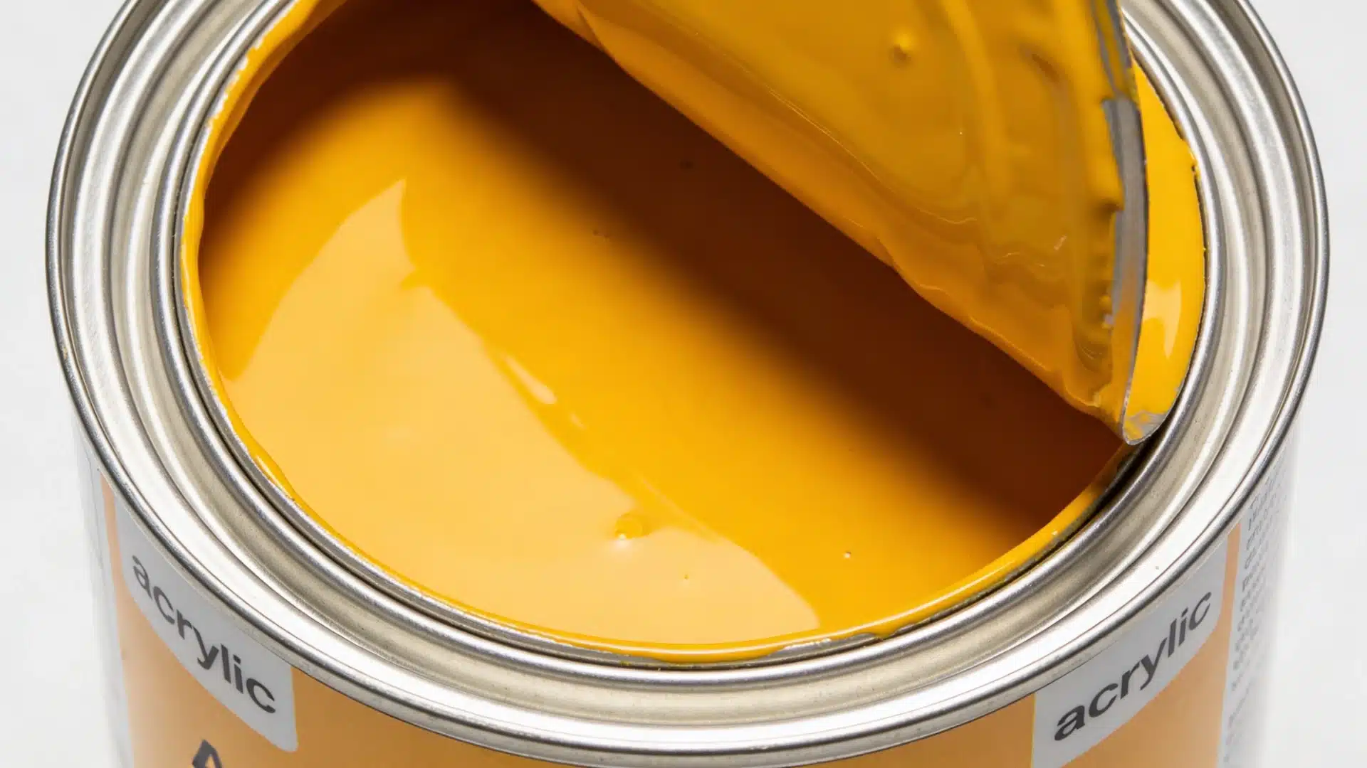Close-up view of an open tin can filled with bright, glossy yellow acrylic paint against a white background.