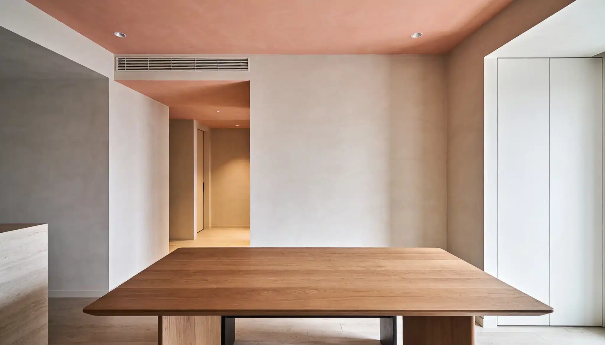 minimal dining room with soft peach ceiling and warm lighting creating an inviting atmosphere