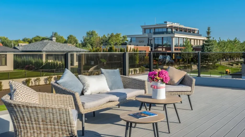 Outdoor patio with wicker seating and pink flowers overlooking modern building and garden