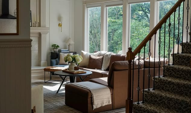 Sunlit living room beside elegant staircase.