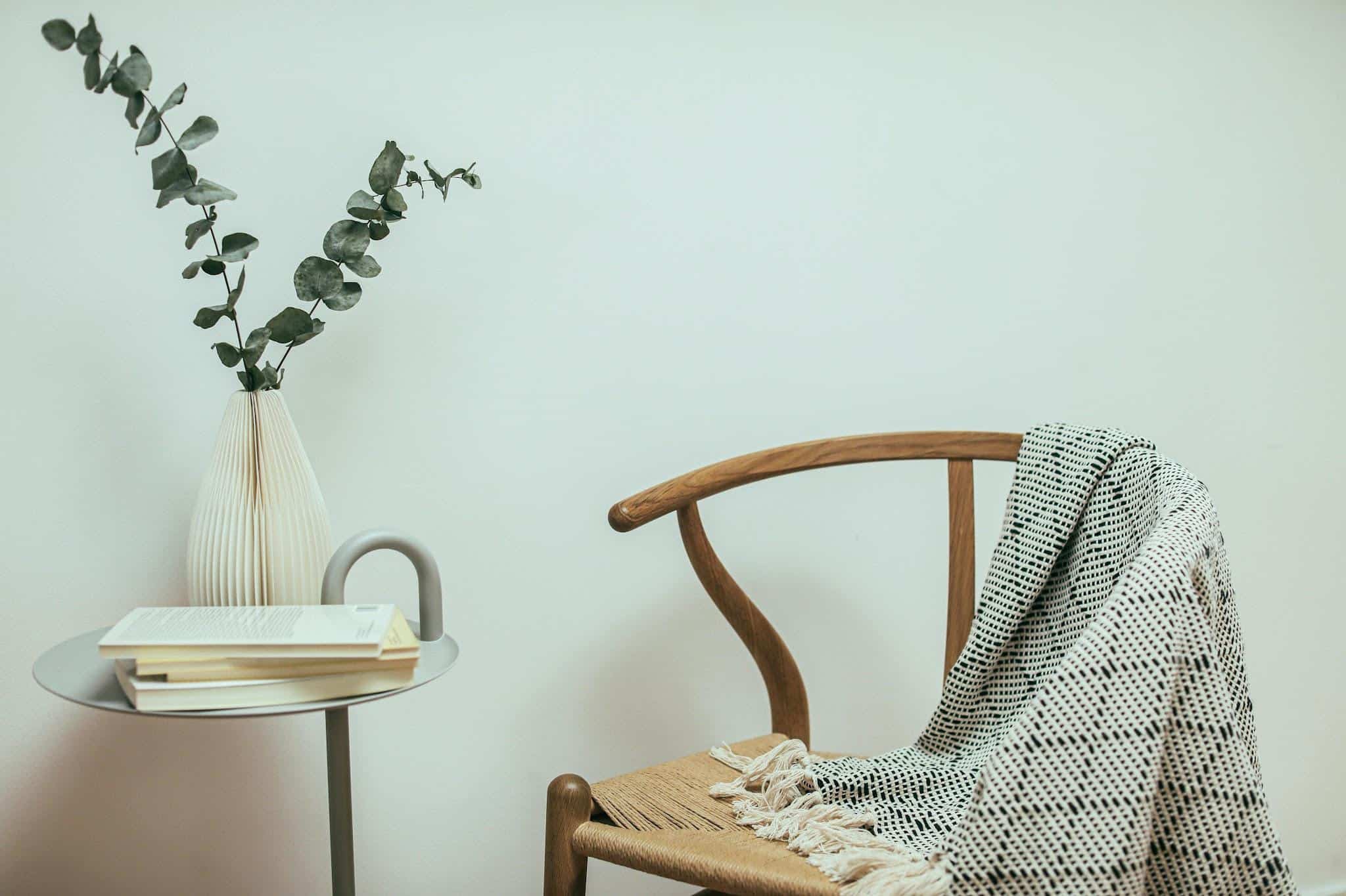 A cozy corner featuring a wooden chair, blanket, and decorative table.