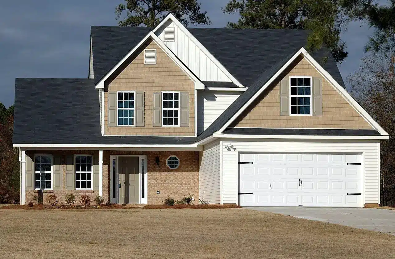Beige and white two-story suburban house with a large garage and shingled roof.