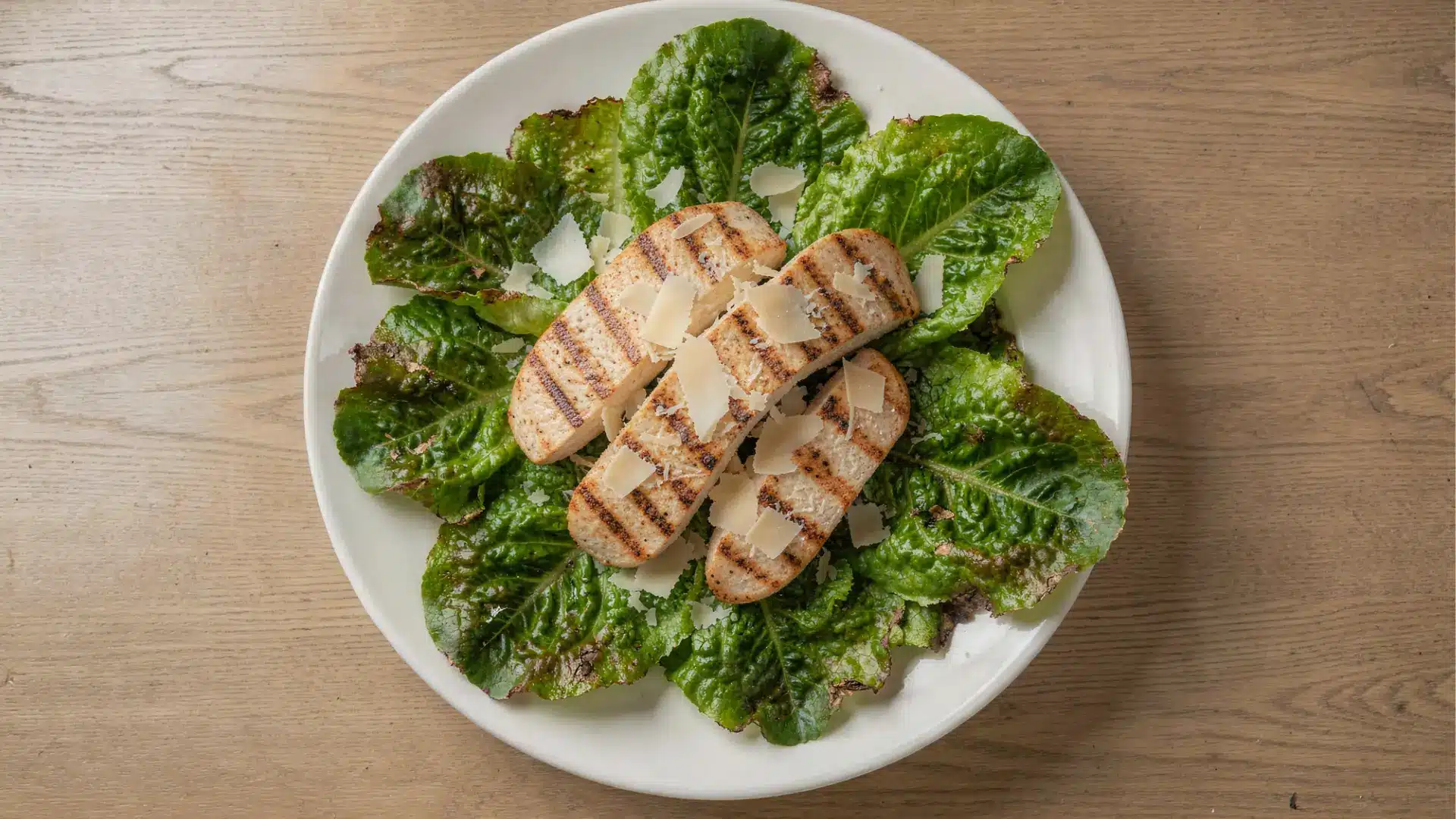 Grilled chicken slices on a bed of romaine lettuce, topped with parmesan shavings