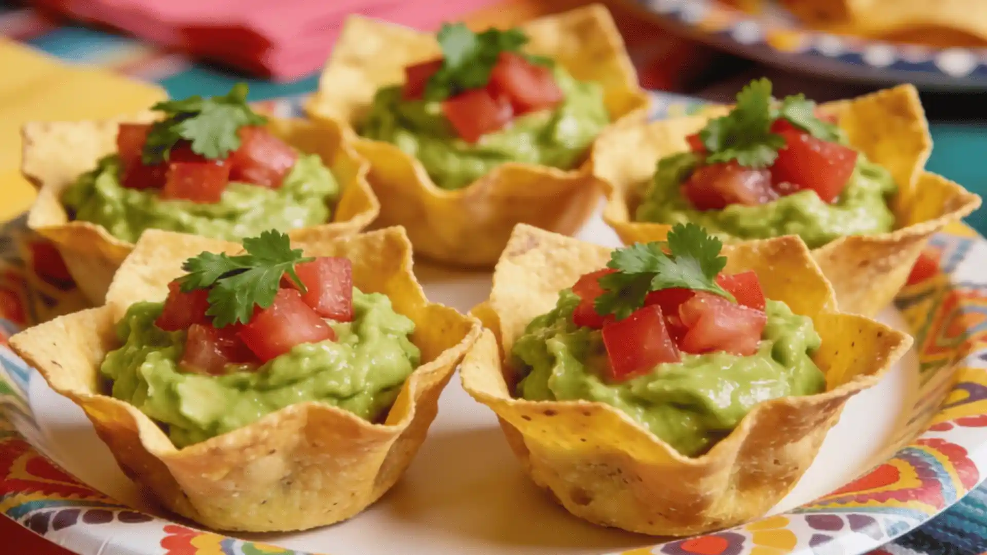 Five crispy tortilla cups filled with guacamole and topped with diced tomatoes and cilantro.