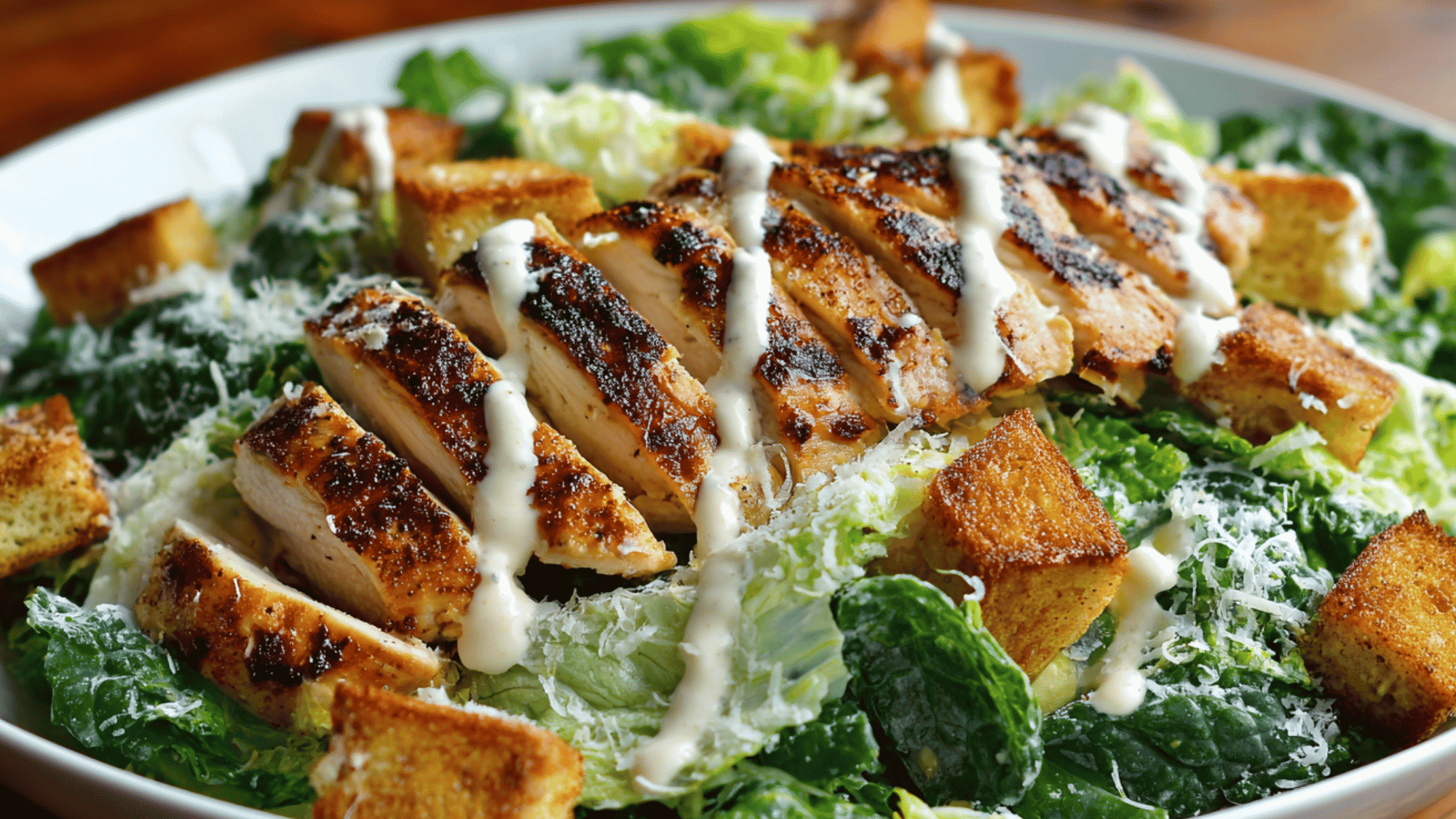 A crisp bed of chopped romaine lettuce tossed with whole grain croutons and a creamy Greek yogurt dressing, topped with thinly sliced grilled chicken breast and a sprinkle of grated Parmesan cheese.