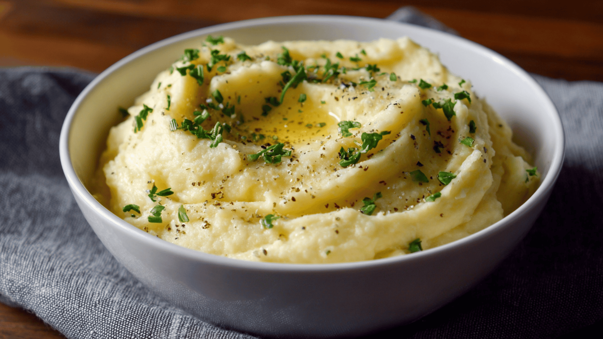 Warm, smooth mashed potatoes garnished with fresh chopped chives in a bowl.
