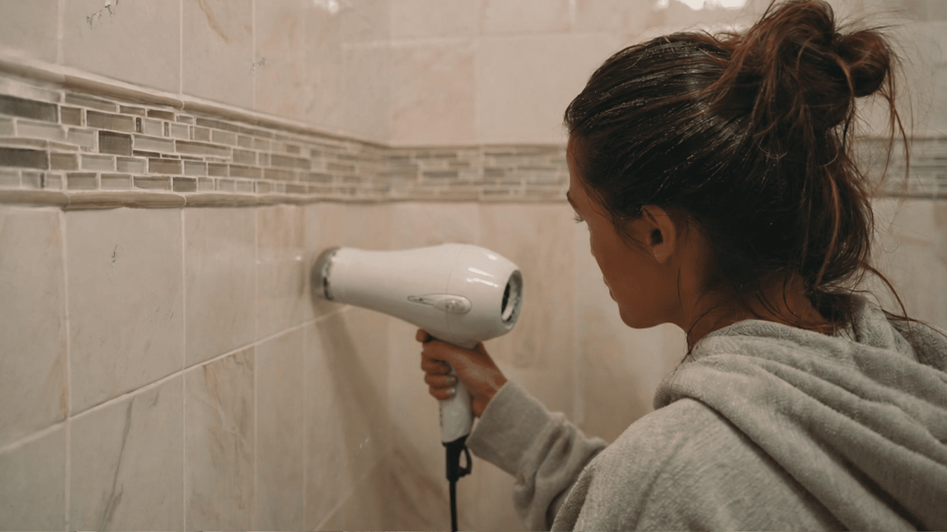 Hand using hair dryer on old tile paint