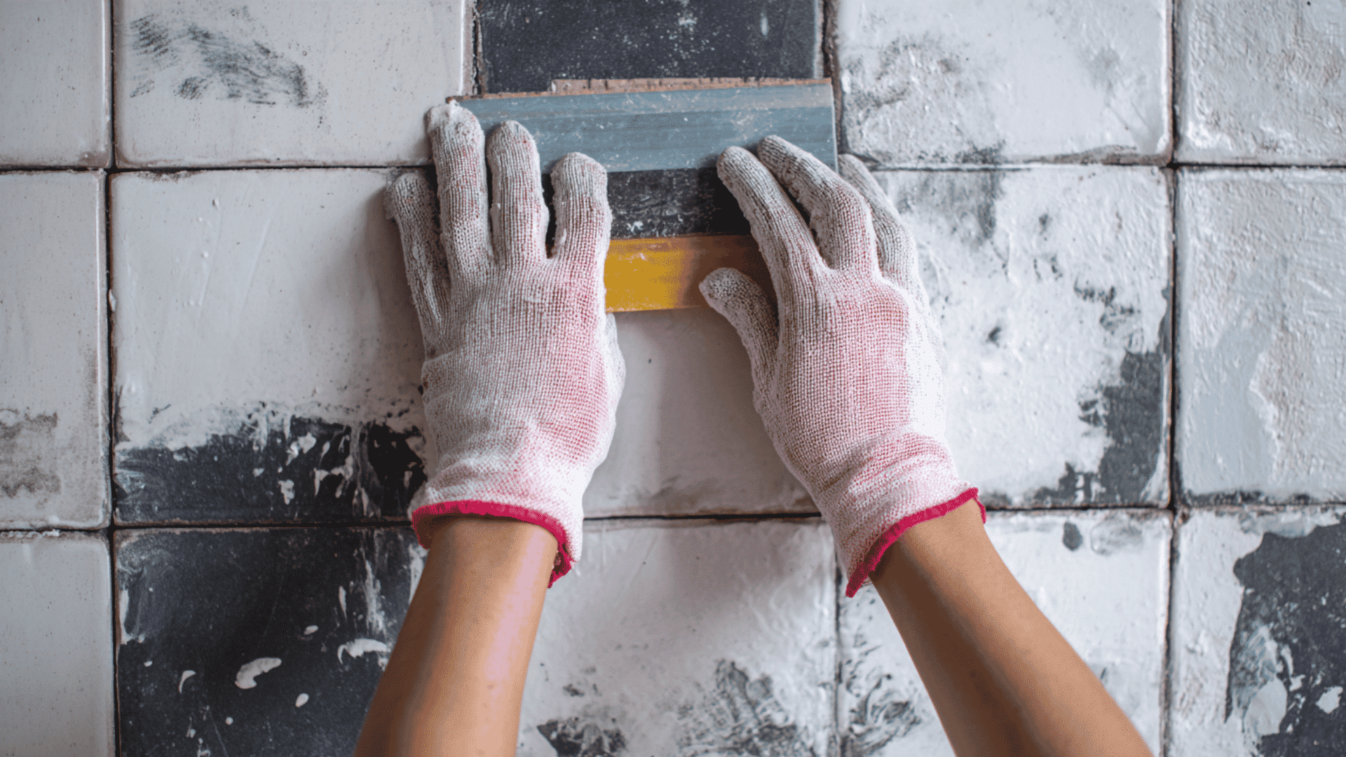 Scraping dried paint off tile with hand