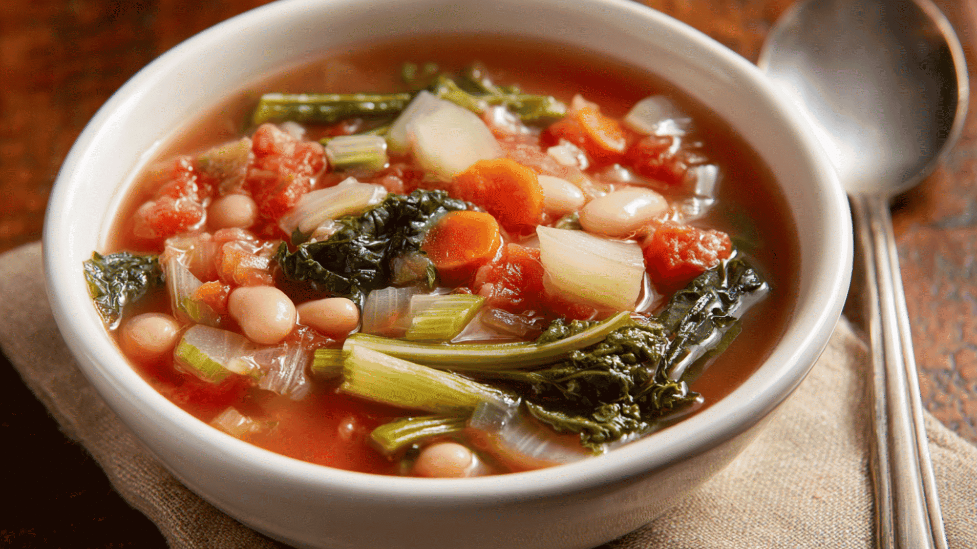 A hearty minestrone soup cooking inside a slow cooker, filled with chopped zucchini, carrots, kidney beans, and diced tomatoes in a seasoned vegetable broth.