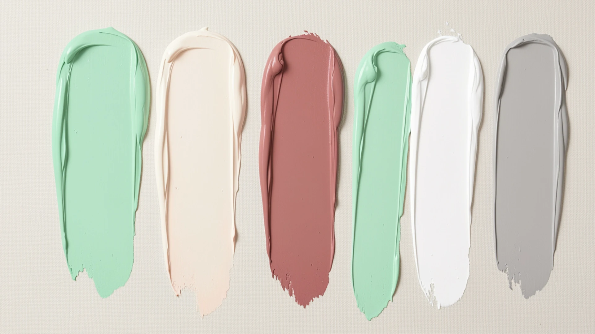 Swatches of pastel paint in mint green, blush pink, dusty rose, white, and gray are displayed on a light background