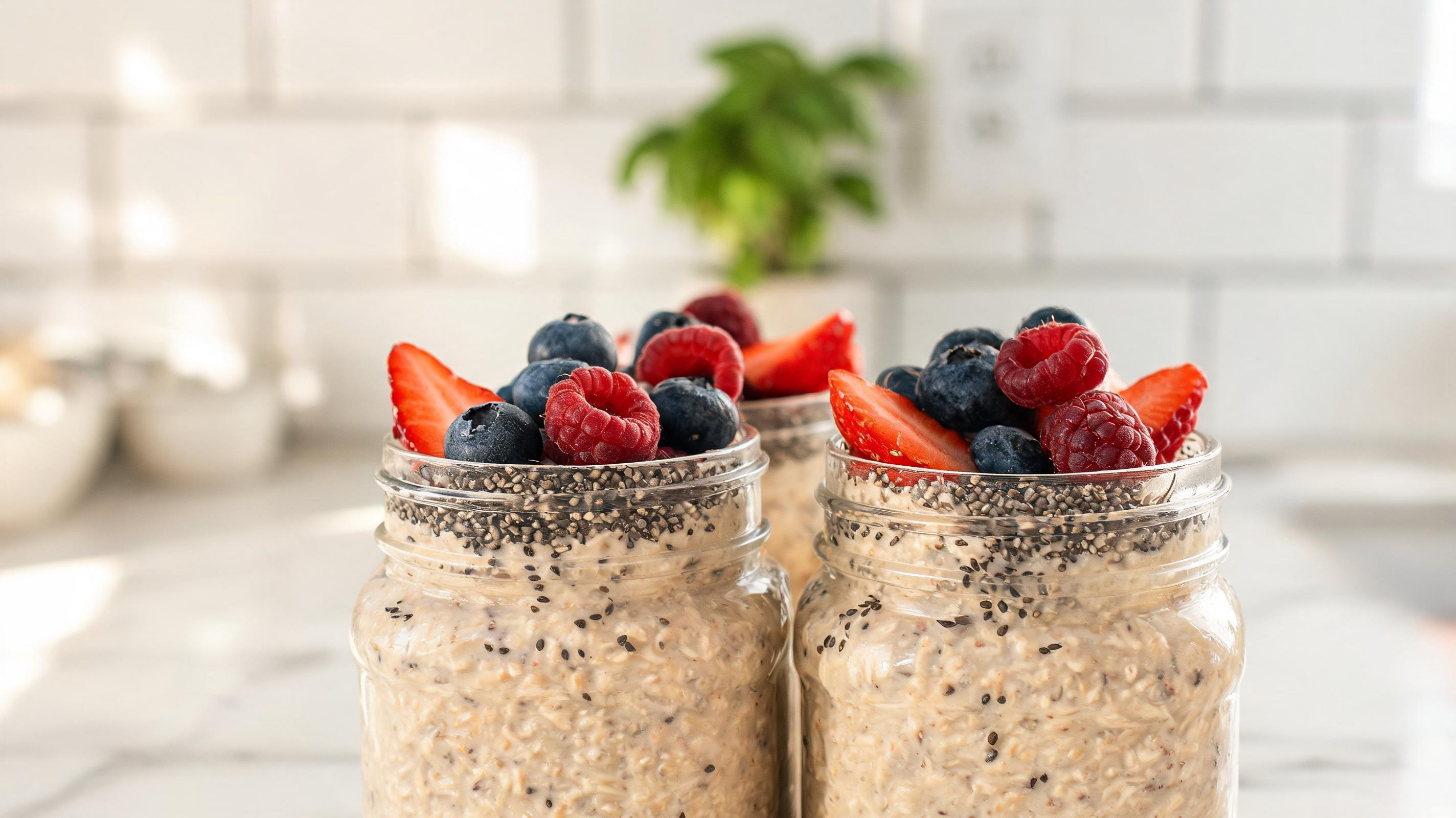 A glass jar filled with creamy overnight oats, chia seeds, and berries.