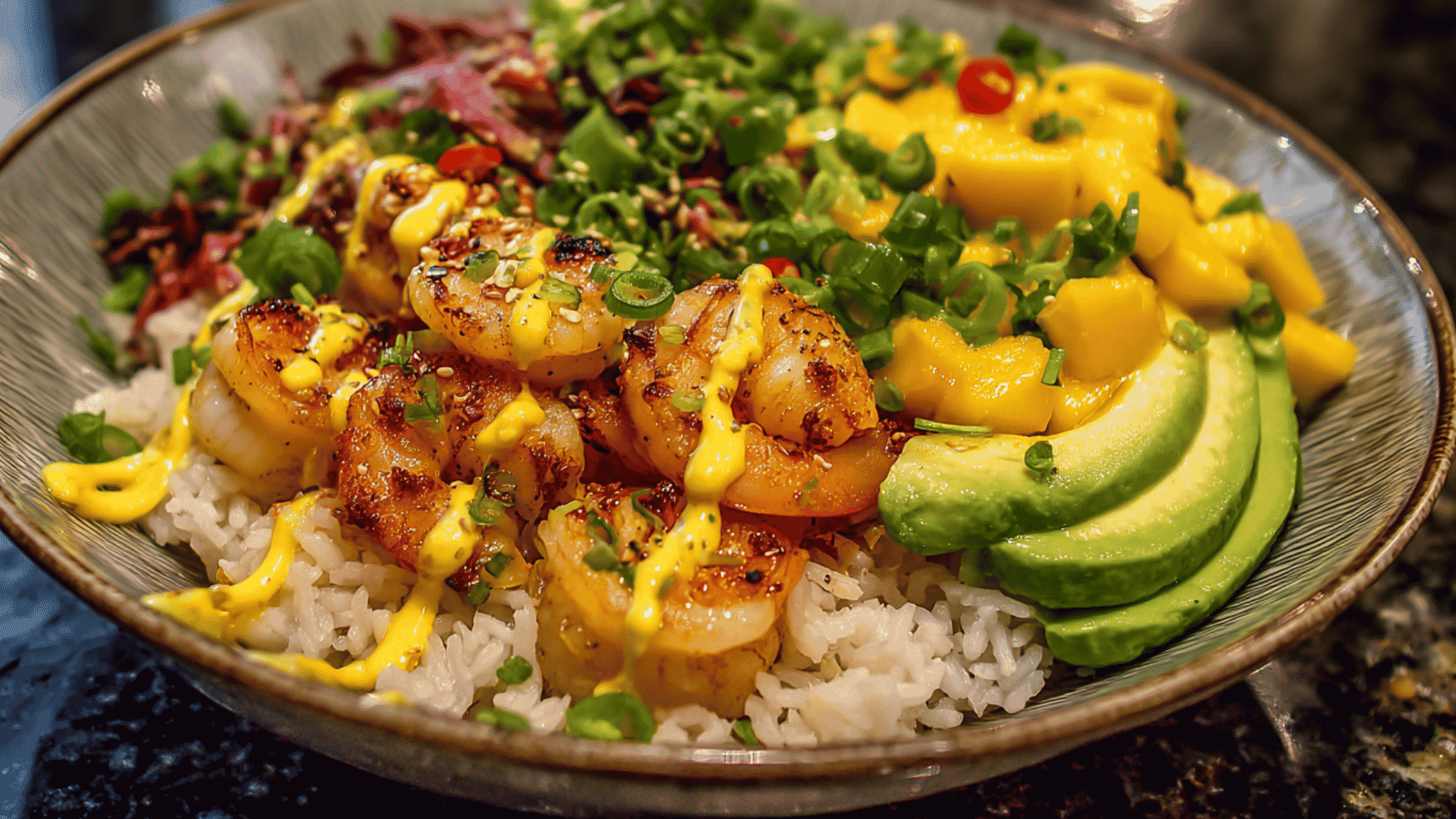 A nutritious shrimp and mango rice bowl featuring a base of fluffy jasmine rice topped with seasoned succulent shrimp, diced sweet mango, sliced creamy avocado, and a light drizzle of chili-lime dressing.