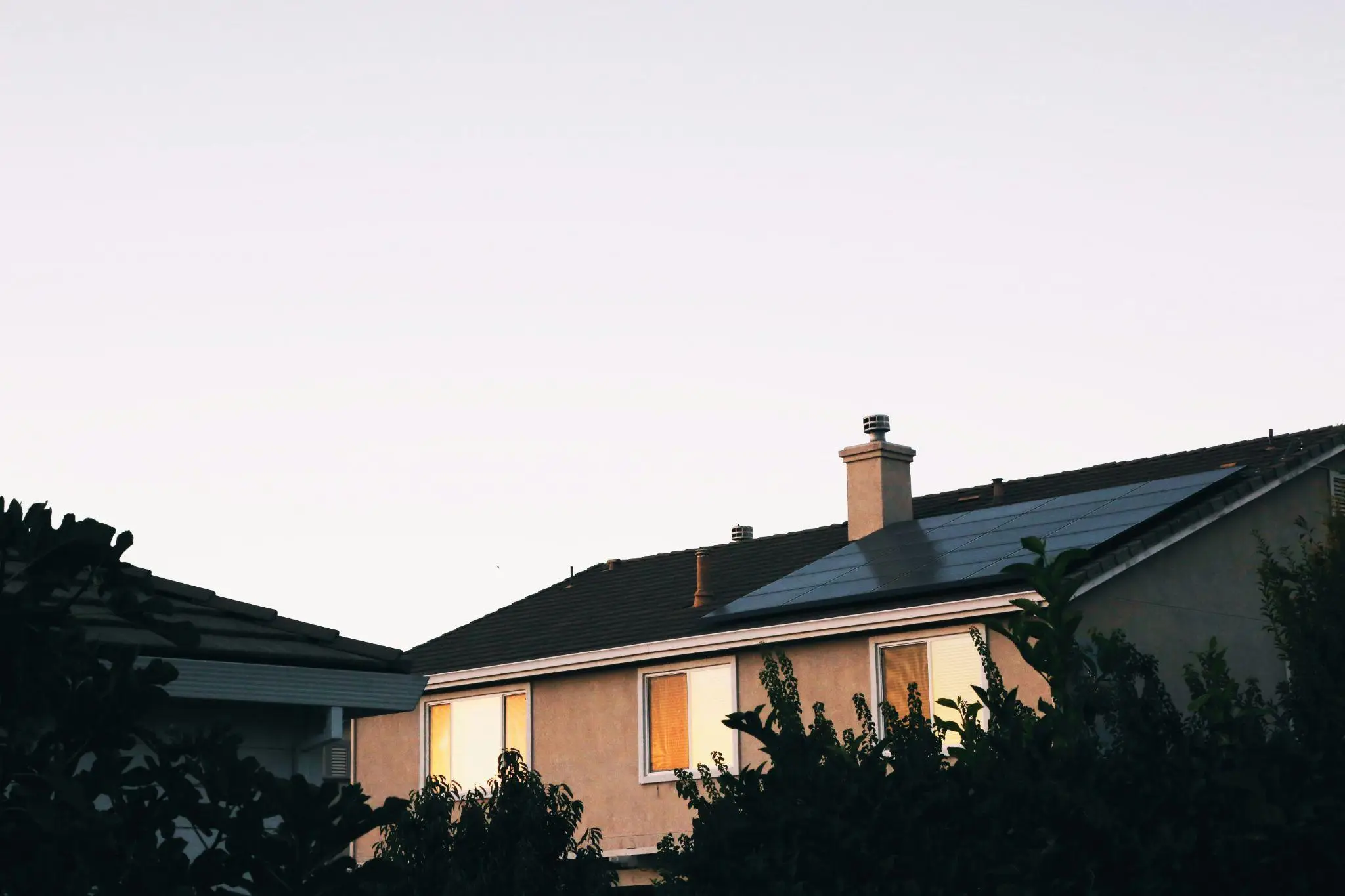 Residential home with solar panels on roof during sunset in suburban neighborhood