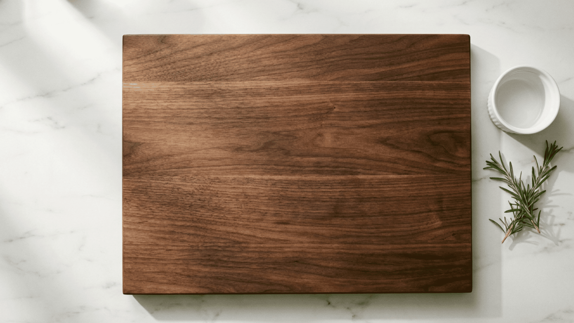 Empty walnut board on white marble countertop overhead shot