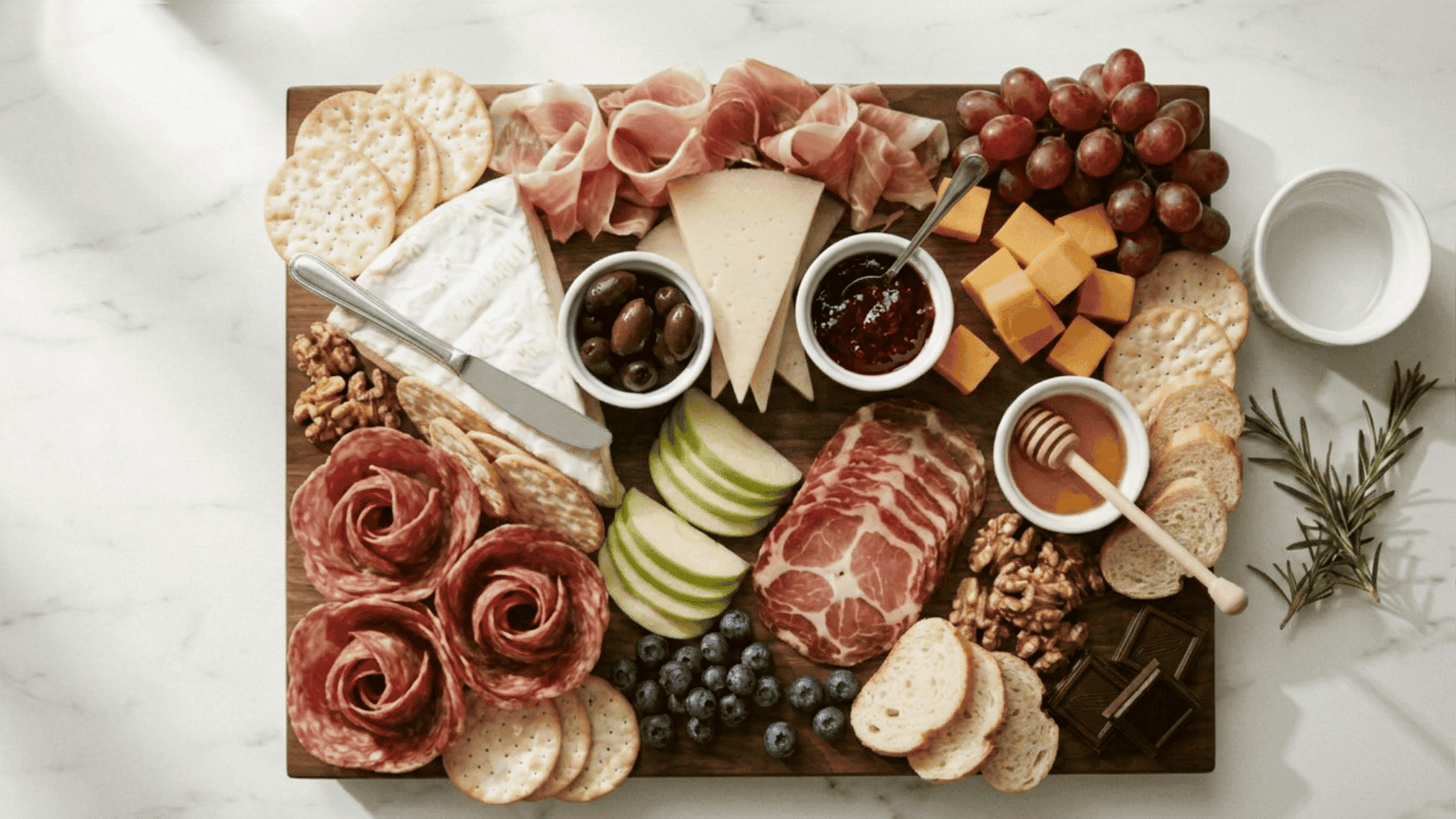 Fully packed charcuterie board with crackers knives and spoons