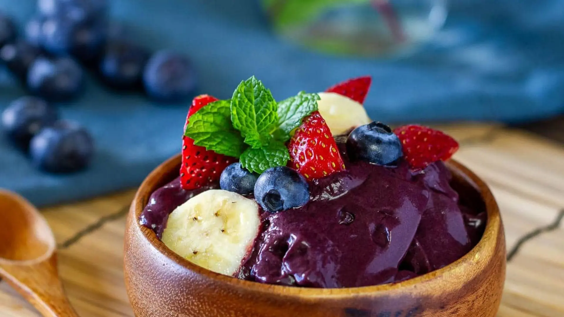 Blueberry smoothie bowl topped with banana slices, fresh blueberries, and a sprig of mint.