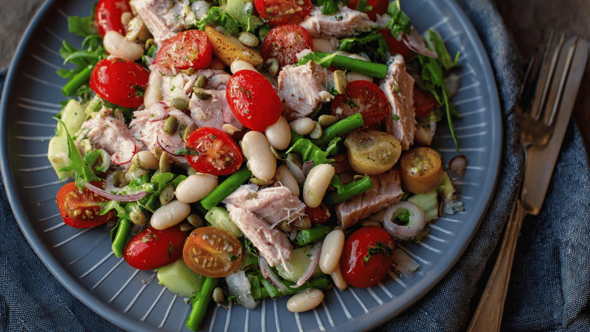 A vibrant and fresh no-cook tuna and white bean salad tossed with finely diced red onion, halved cherry tomatoes, and freshly chopped parsley, dressed lightly with olive oil and lemon juice.