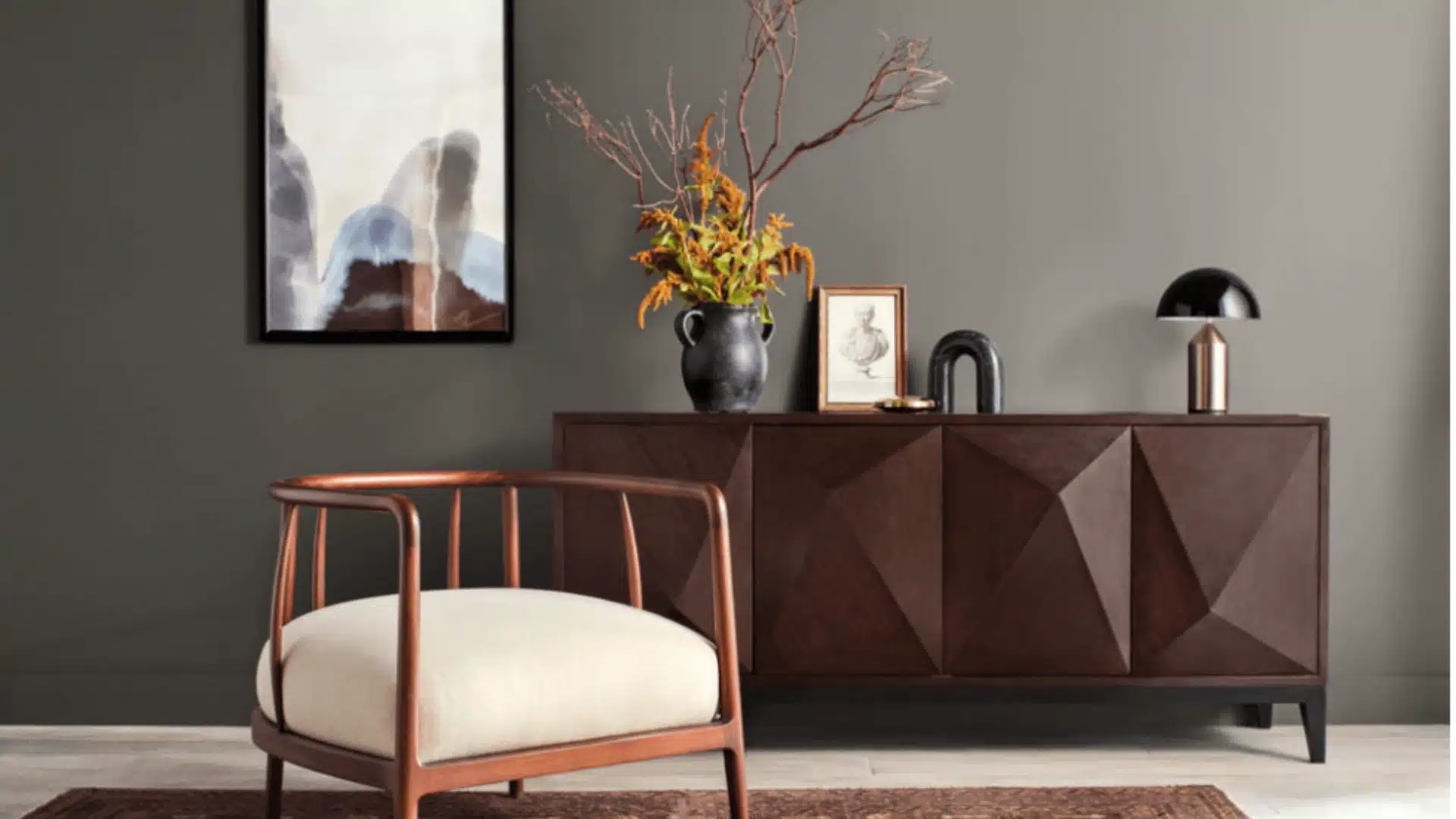A stylish living room with a wooden sideboard and artwork, showcasing a sophisticated gray-brown palette and warm details.