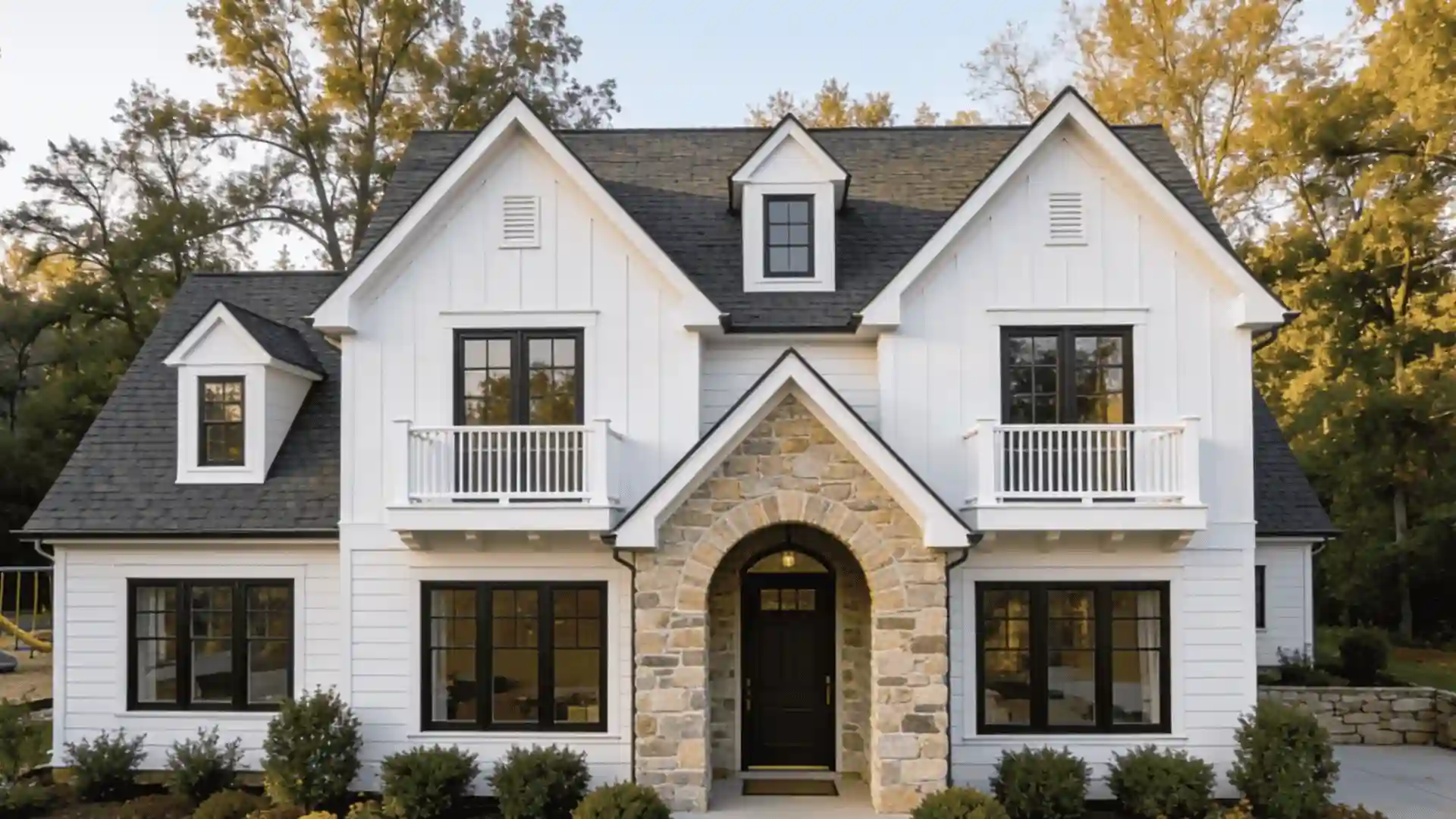 Modern white victorian house with black windows and a stone arched entryway.