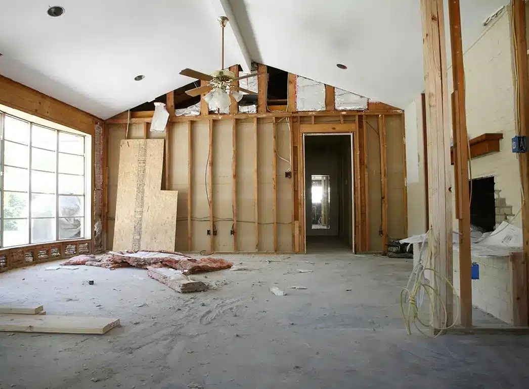 Unfinished home renovation with exposed wooden framing and ceiling fan in bright room
