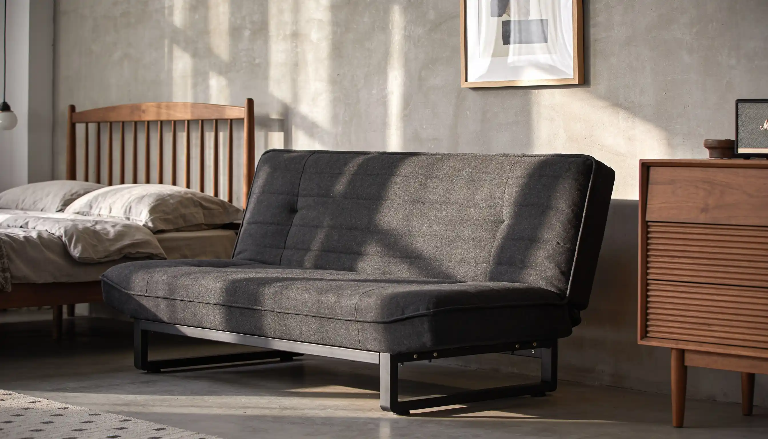 A click clack charcoal sofa with adjustable backrest that can be folded flat into a bed position featuring a modern minimalist design