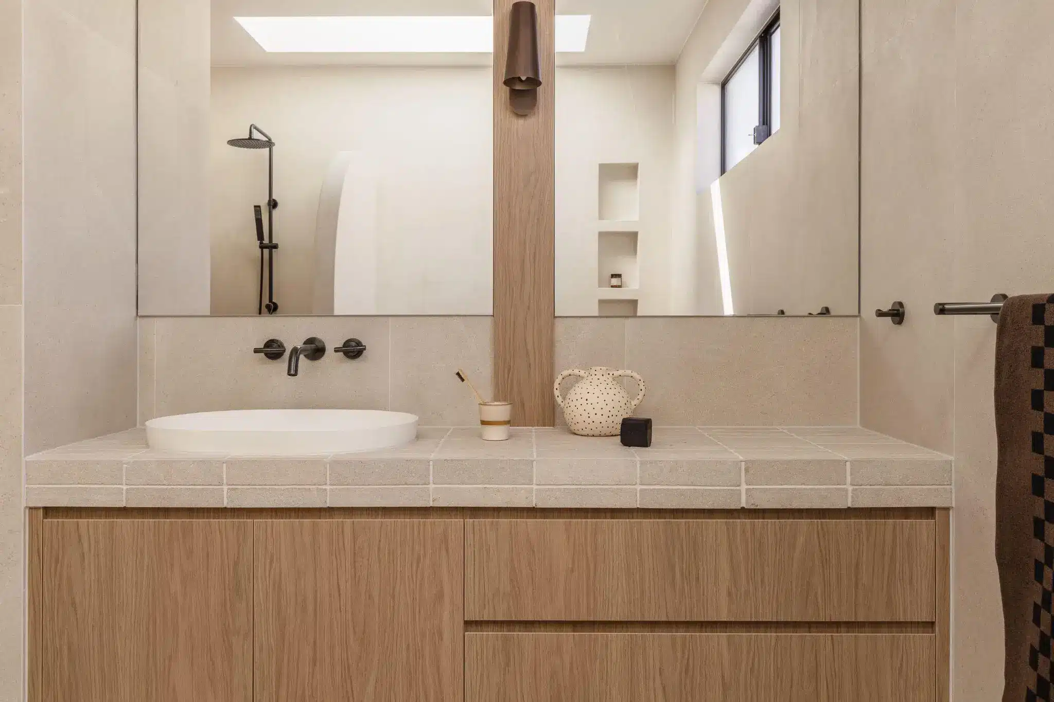 Modern bathroom with wood vanity, circular sink, and wall-mounted fixtures under soft lighting