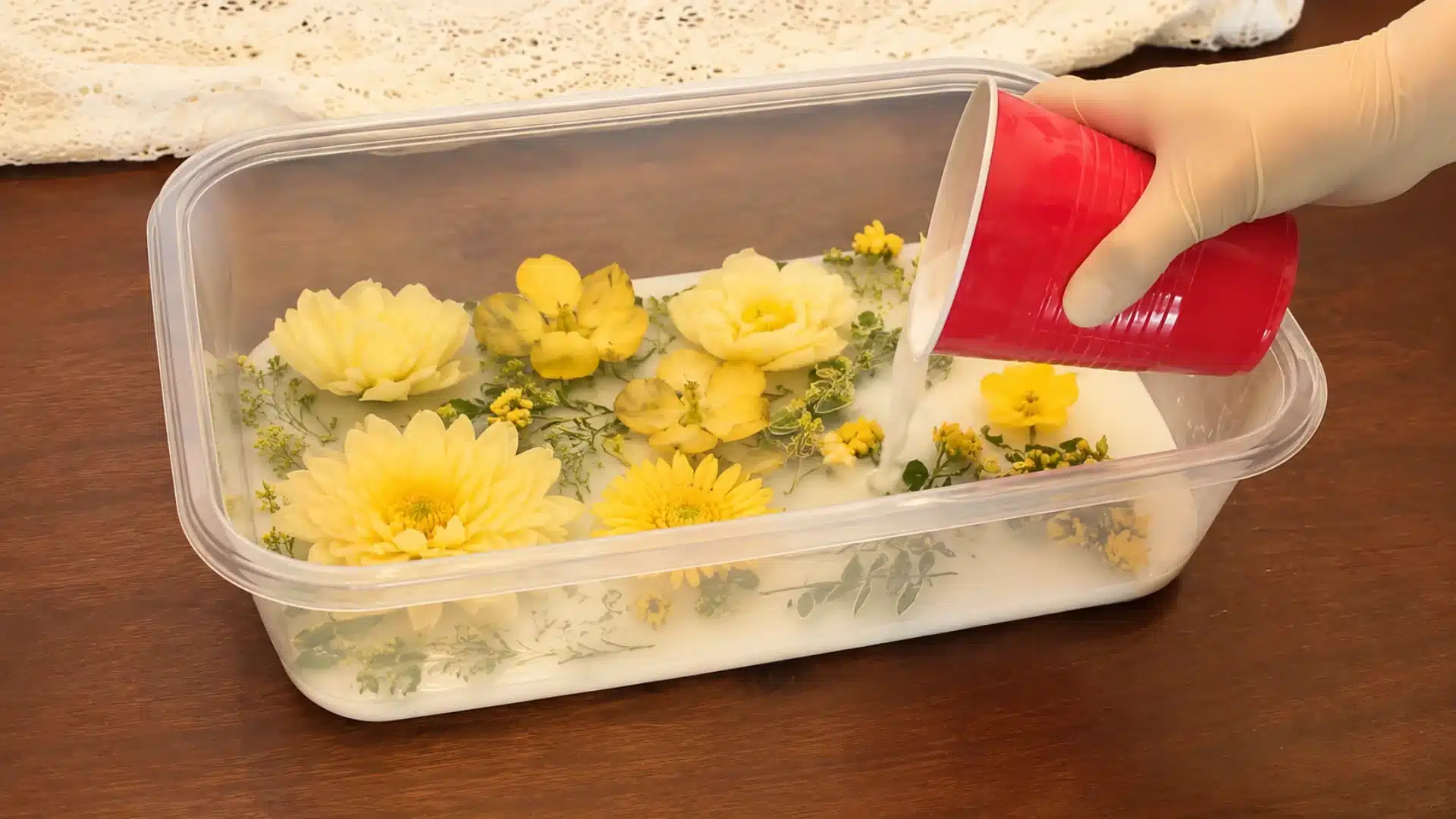 Yellow flowers being covered with silica in a plastic container.