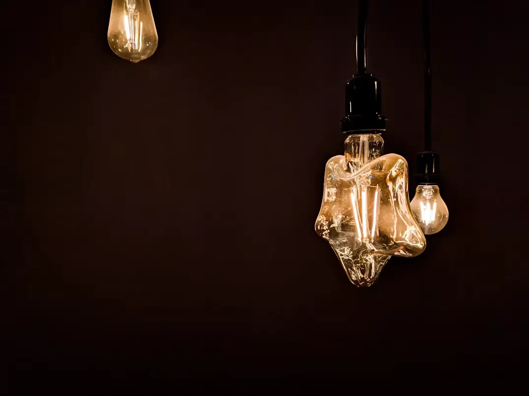 Decorative pendant lights with exposed bulbs illuminated against dark background