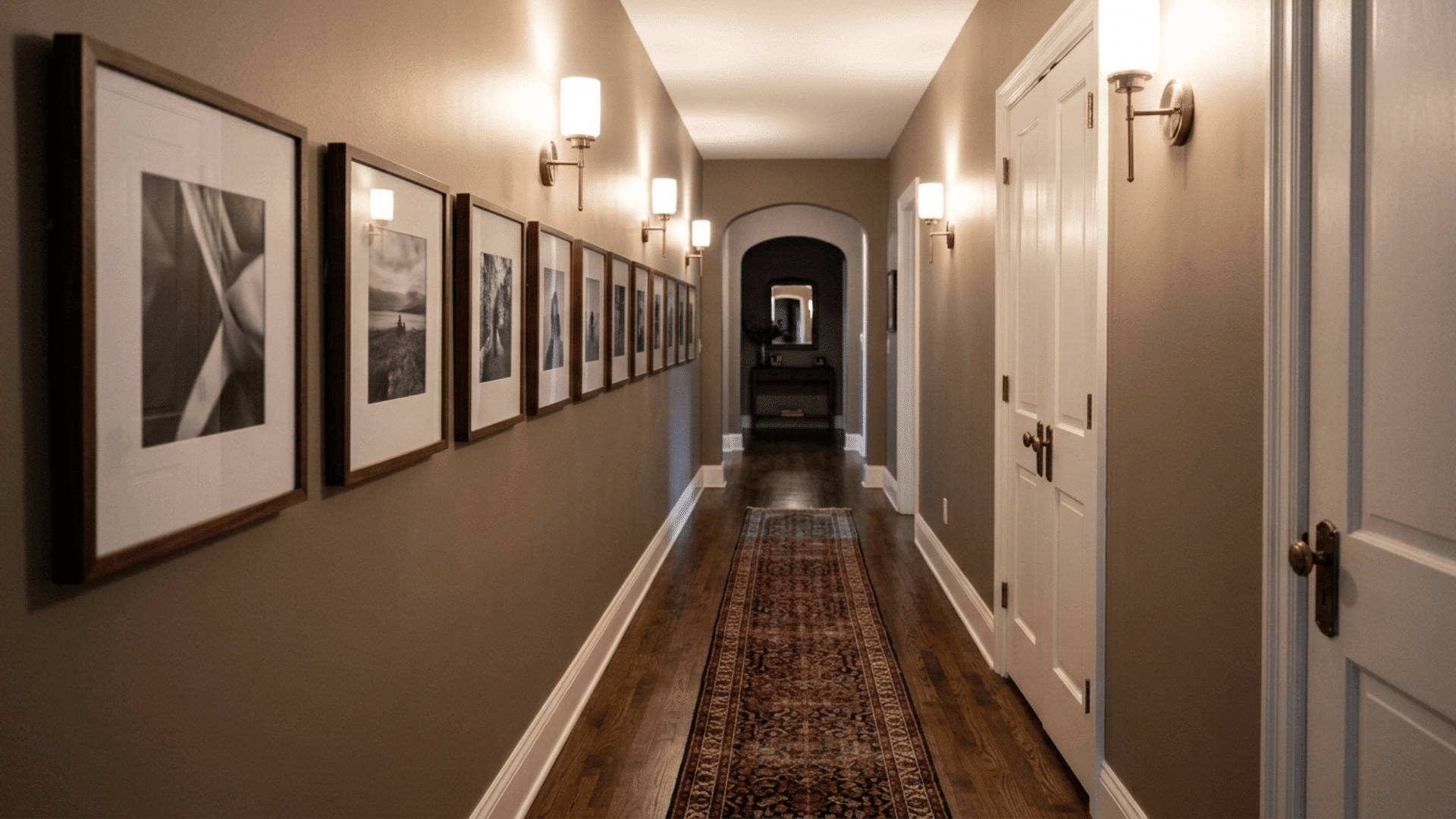 narrow hallway with a gallery wall, runner rug, and wall sconces