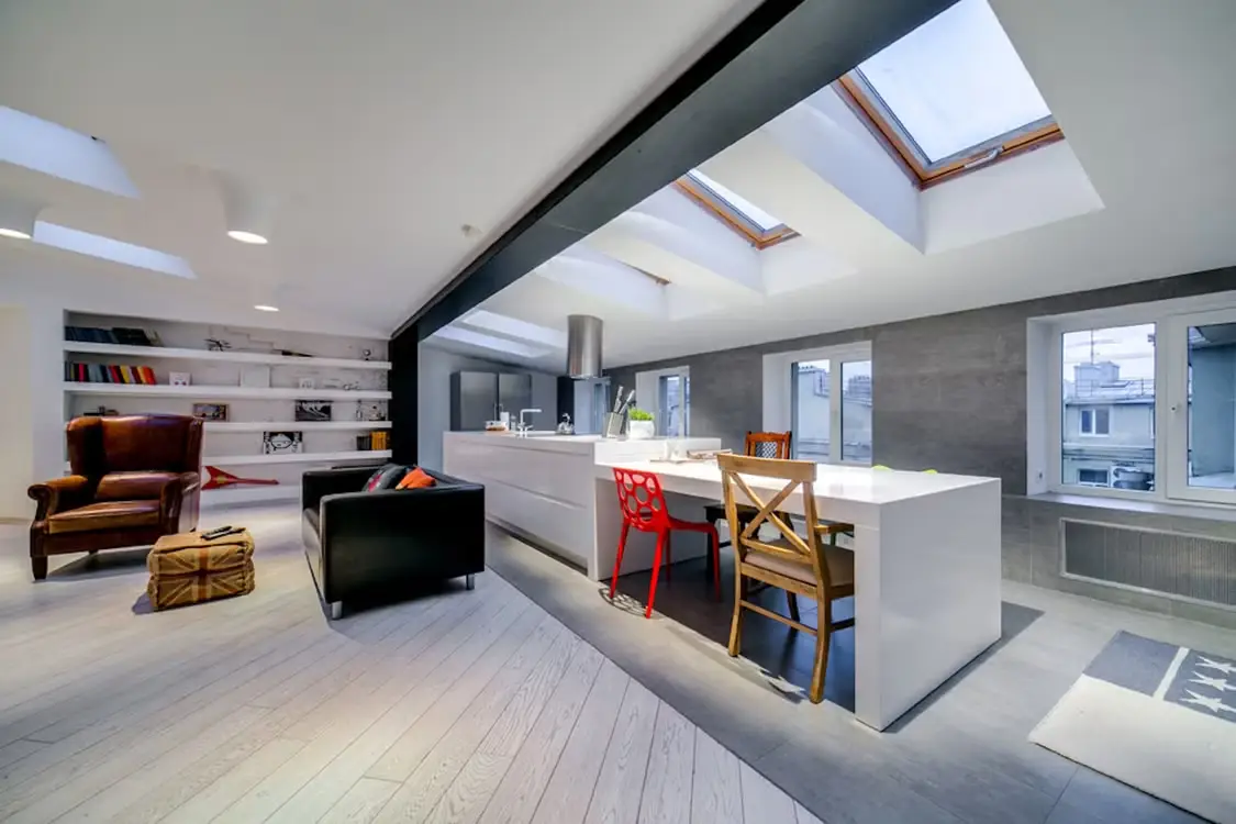 Modern loft apartment with skylights, featuring kitchen island and eclectic seating arrangement