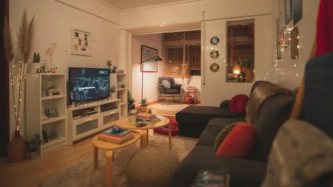 Cozy living room with large sofa, coffee tables, and wall-mounted TV under warm lighting