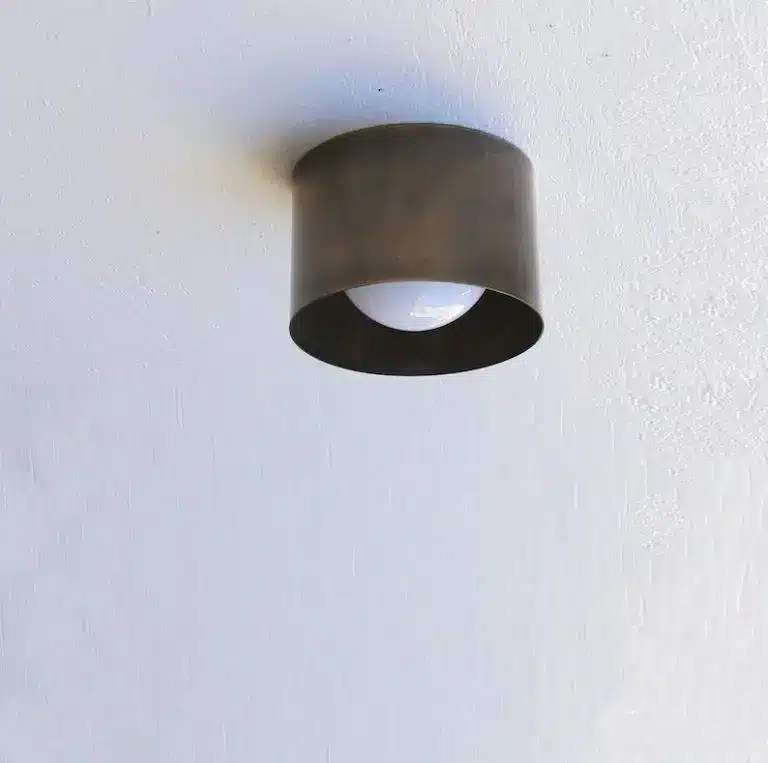 Ceiling-mounted bronze light fixture with visible bulb on white textured ceiling