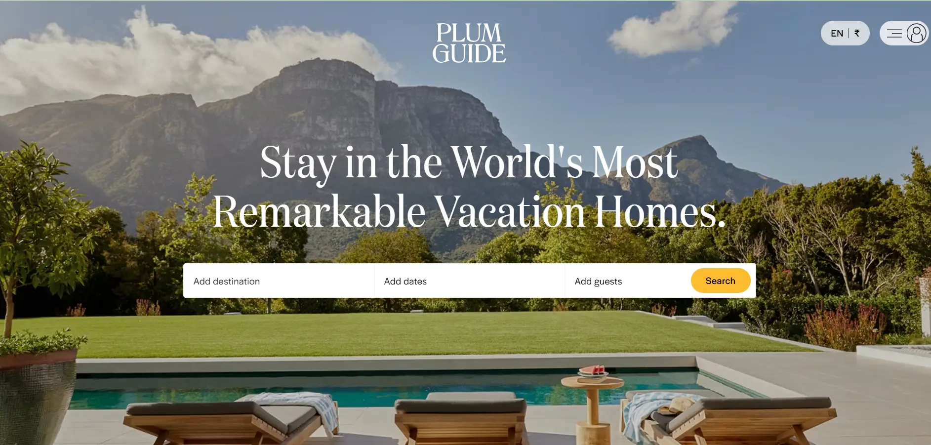 Lounge chairs by pool with mountains in background under clear sky