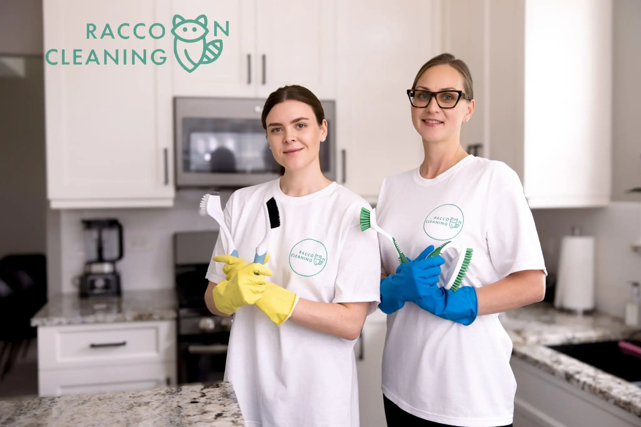 Two women in cleaning uniforms holding brushes in a modern kitchen setting