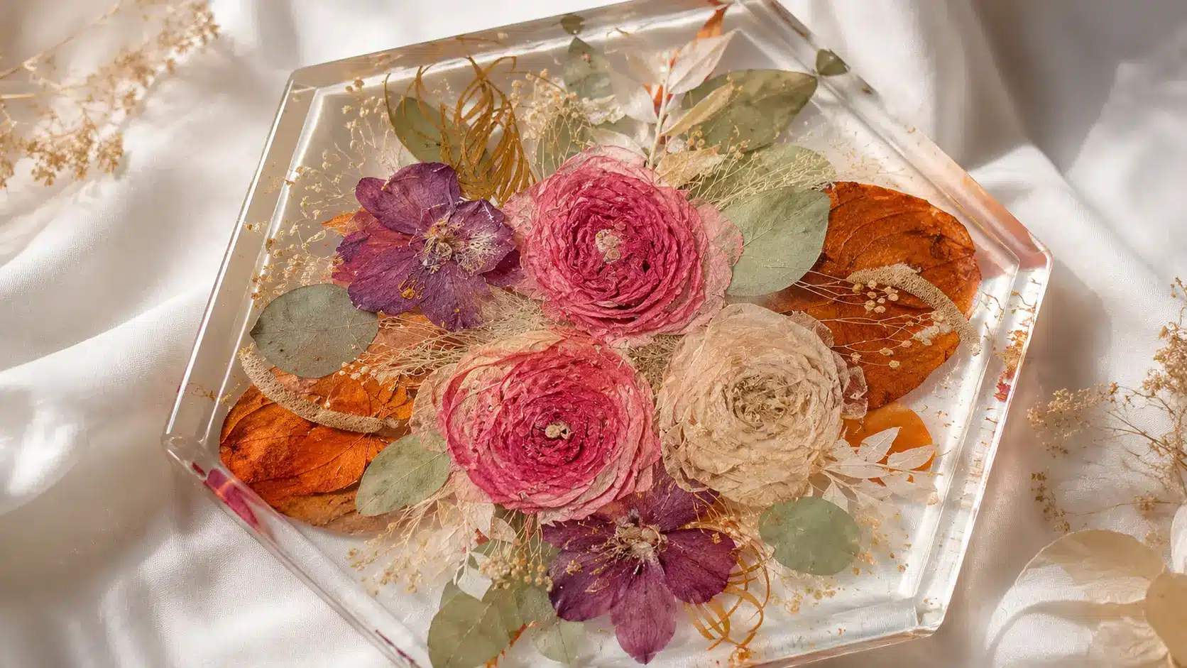 Colorful pressed flowers and leaves preserved in a clear resin tray.