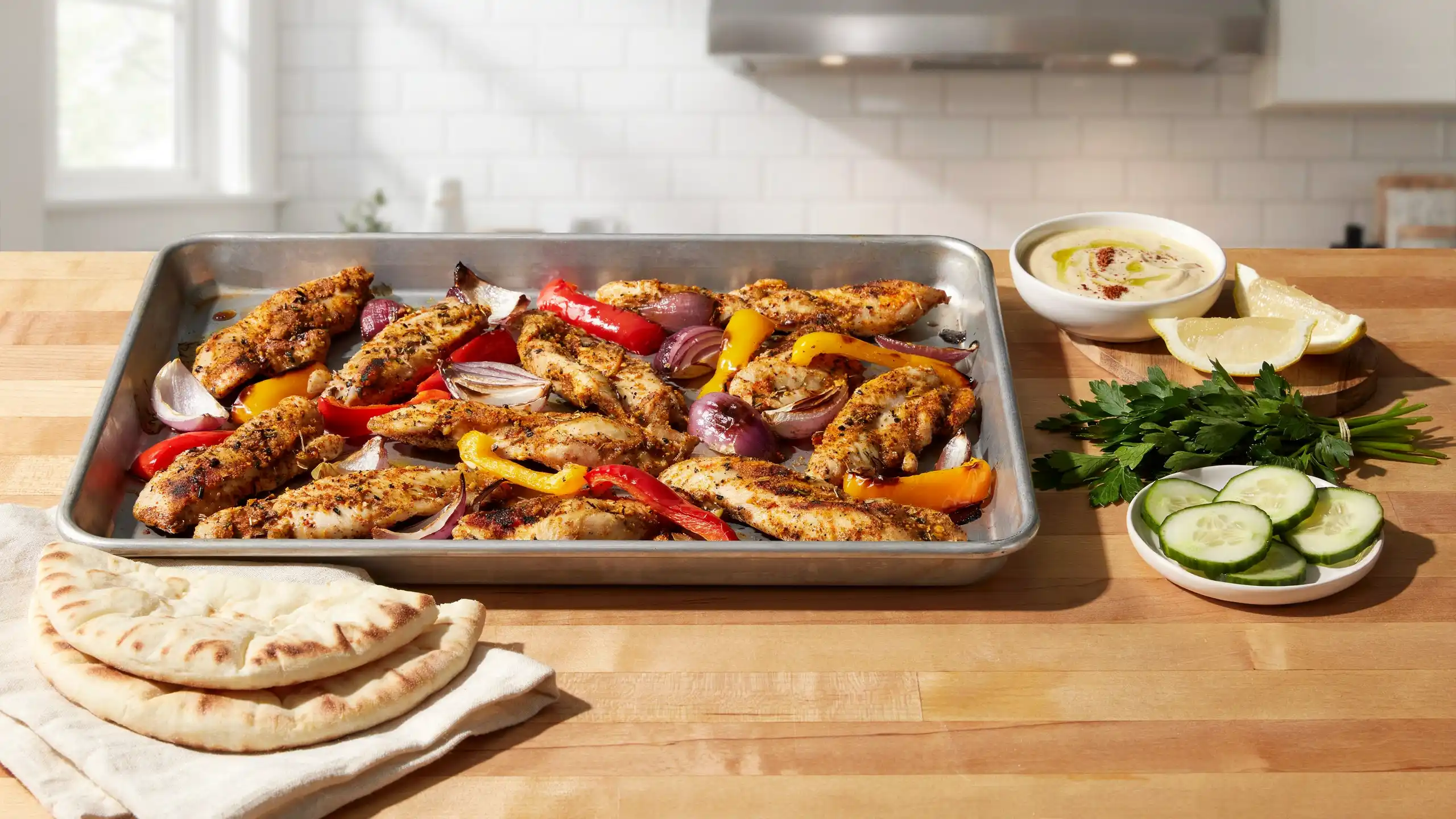 sheet pan chicken shawarma with roasted chicken peppers onions pita bread lemon and creamy garlic sauce