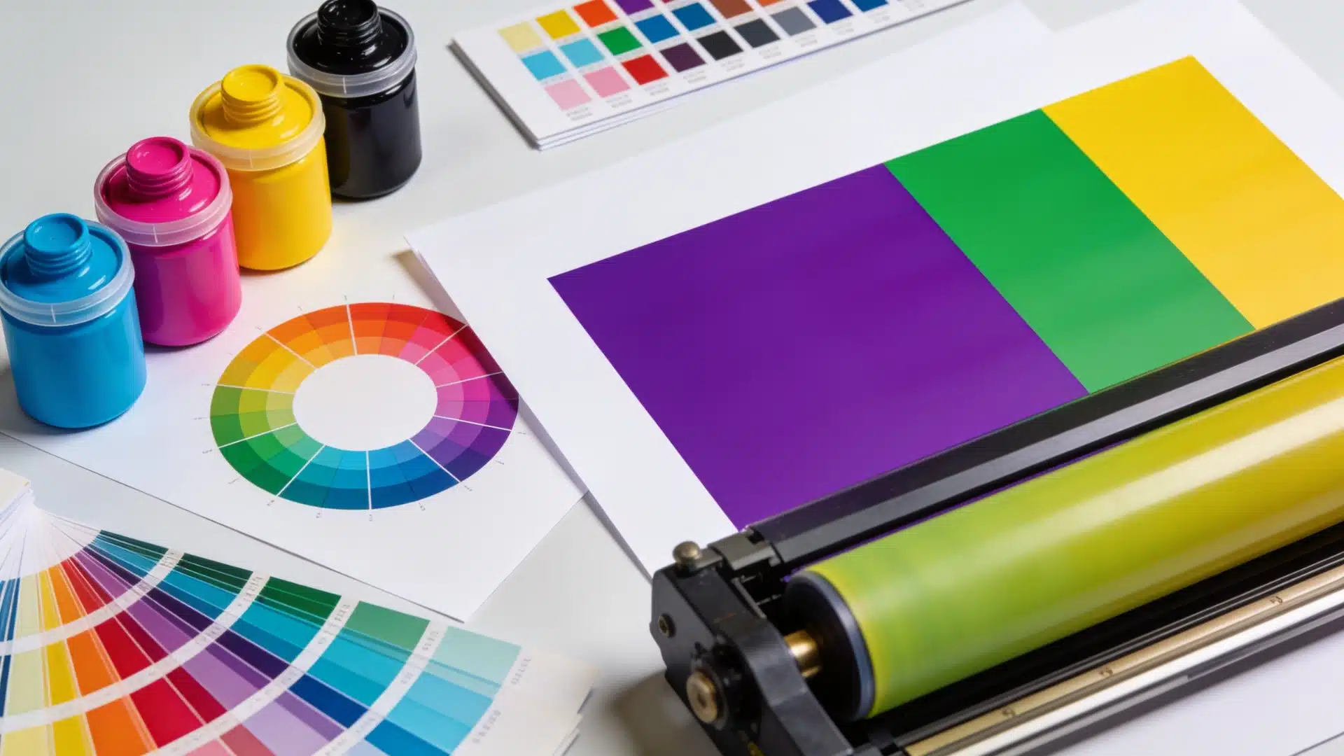 CMYK ink pots and color charts surround a print roller with purple, green, and yellow samples shown.